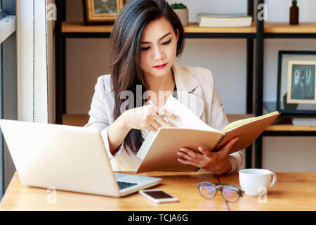 Junge asiatische Geschäft Frau am Arbeitsplatz arbeiten. schöne asiatische Frau in lässiger Anzug mit Lesung Buch arbeiten, für die Einhaltung oder das Interview in m vorbereiten Stockfoto