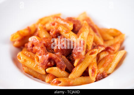Italienische Amatriciana Pasta mit Tomatensauce und geräuchertem Speck auf weiße Platte serviert. Stockfoto
