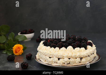 Torte Pavlova mit Brombeeren und Schlagsahne, auf einem dunklen Hintergrund entfernt Stockfoto