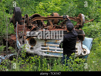 Ein Besucher nimmt Fotos eines havarierten auto in die Sperrzone von Tschernobyl in der verlassenen Stadt Pripyat. Die HBO-TV-Miniserie Tschernobyl, die Premiere in den USA und in England auf Mai 2019, zeigt die Zeit nach der Katastrophe, einschließlich der Reinigung und die anschließende Untersuchung. Der Erfolg HBO TV-Miniserie Tschernobyl Prüfung schlimmste Atomunfall von Tschernobyl hat sich die Anzahl der Touristen, die Anlage und die geisterhaften verlassenen Stadt, dass die Nachbarn es für sich selbst, und der Tourismus Industrie der Region beigetragen zu haben, mit den Chefs der Führungen zu Che zu sehen, angetrieben Stockfoto