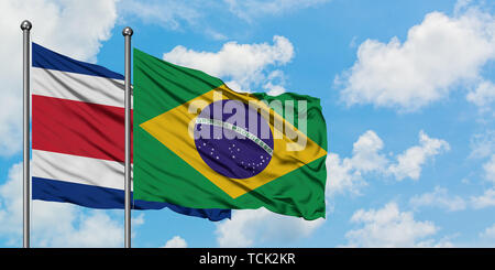 Costa Rica und Brasilien Flagge im Wind gegen Weiße bewölkt blauer Himmel zusammen. Diplomatie Konzept, internationale Beziehungen. Stockfoto