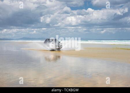 Schwarz Hyundai Santa Fe 4x4 Geländewagen Laufwerke auf dem Sandstrand von Ninety Mile Beach im Wasser, weit im Norden Bezirk, Northland, North Island Stockfoto