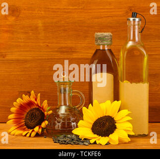 Öl in Flaschen, Sonnenblumen und Samen, auf hölzernen Hintergrund Stockfoto