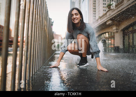 Mädchen spielen und tanzen um auf einer nassen Straße Stockfoto