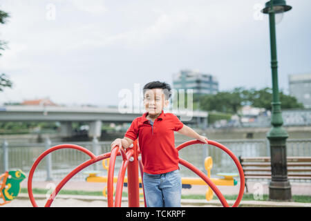 Wenig asiatischen Jungen Reiter ein Schwingen und freut sich Stockfoto