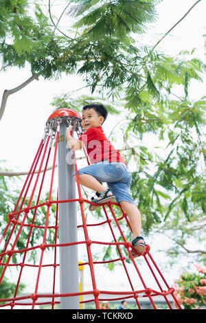 Little Boy in Gap klettern auf Jungle Gym im Park Stockfoto