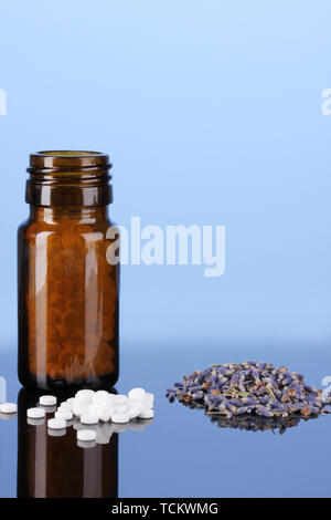 Flasche mit Pillen und Kräutern auf blauem Hintergrund Konzept der Homöopathie Stockfoto