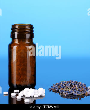 Flasche mit Pillen und Kräutern auf blauem Hintergrund Konzept der Homöopathie Stockfoto