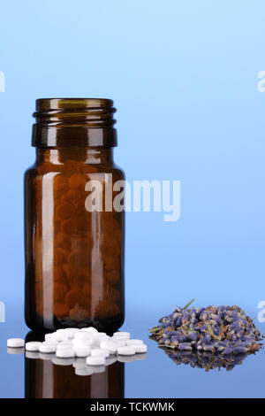 Flasche mit Pillen und Kräutern auf blauem Hintergrund Konzept der Homöopathie Stockfoto