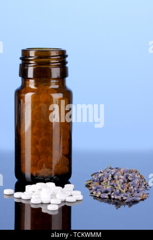 Flasche mit Pillen und Kräutern auf blauem Hintergrund Konzept der Homöopathie Stockfoto