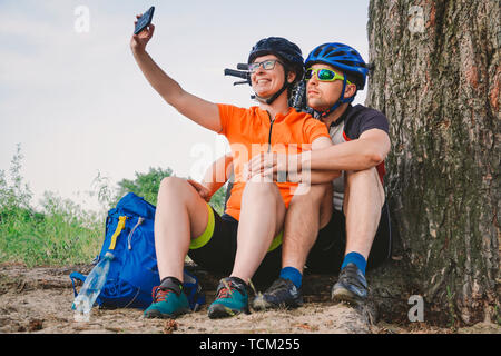 Glückliches Paar mit Mountainbike unter selfie Smartphone im Freien. Ein glückliches Paar, die einen aktiven Lebensstil, in den Wäldern in der Nähe des Baums zu Stillstand führen. Stockfoto