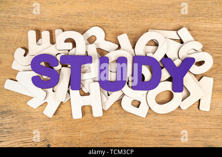 Violett Wort studieren, legte aus Holz Buchstaben auf einem Haufen von verschiedenen Buchstaben liegen auf einem Schreibtisch aus Holz Stockfoto