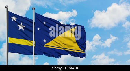 Curacao und Tokelau flag waving im Wind gegen Weiße bewölkt blauer Himmel zusammen. Diplomatie Konzept, internationale Beziehungen. Stockfoto