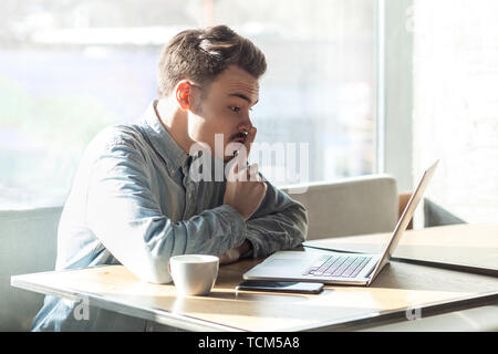 Werden Leise bitte! Seitenansicht Portrait von schweren bärtige junge Freiberufler in blaues Hemd Sitzen im Cafe und Videokonferenz auf Laptop, schlanke Finger Stockfoto