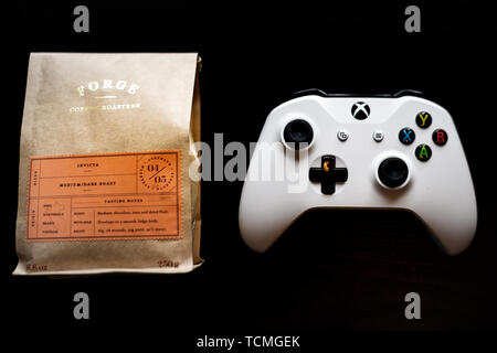 Xbox Spiele controller saß neben einem Beutel gemahlenen Kaffee gegen einen dunklen schwarzen Hintergrund Stockfoto