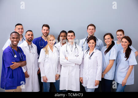 Portrait von Happy multirassischen Medial Mannschaft gegen grauer Hintergrund Stockfoto