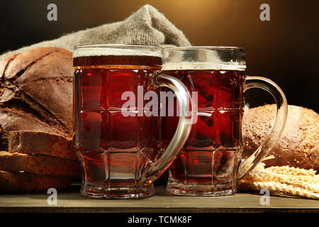 Seidel von Kwass und Roggen Brot mit Ohren, auf Holztisch auf braunem Hintergrund Stockfoto