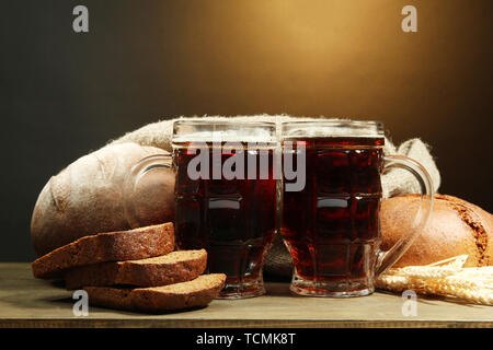Seidel von Kwass und Roggen Brot mit Ohren, auf Holztisch auf braunem Hintergrund Stockfoto