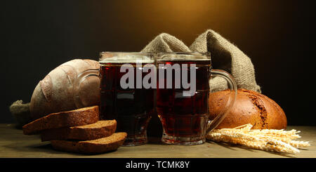 Seidel von Kwass und Roggen Brot mit Ohren, auf Holztisch auf braunem Hintergrund Stockfoto