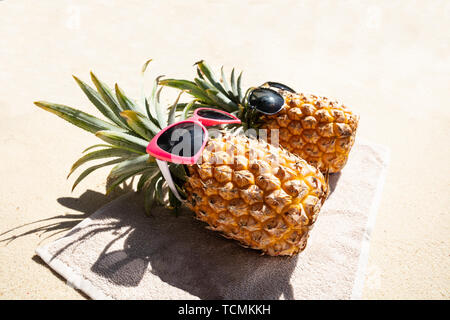 Eine Ansicht von zwei Ananas liegen auf dem Handtuch am Strand Stockfoto