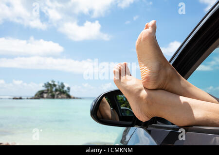 Nahaufnahme der durchgestrichene Frau Bein Aus dem Auto Fenster am Strand Stockfoto