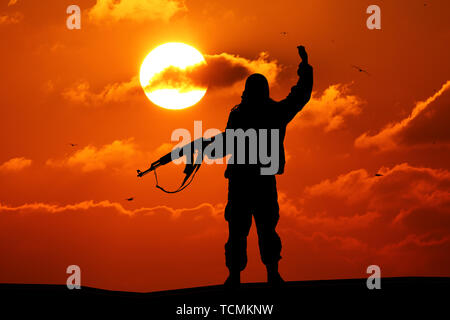 Silhouette der militärischen Soldat oder Offizier mit Waffen bei Sonnenuntergang. schoß, Gewehr, bunte Himmel, Berge, Hintergrund Stockfoto