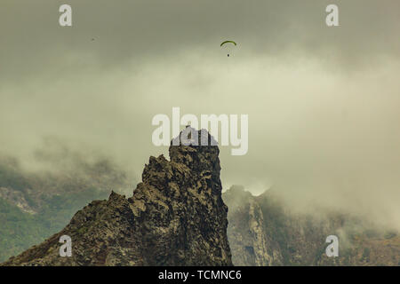 Lonly Gleitschirm zwischen niedriger Dichte Wolken und Berg in der Nähe von Garachico, Teneriffa, Spanien Stockfoto