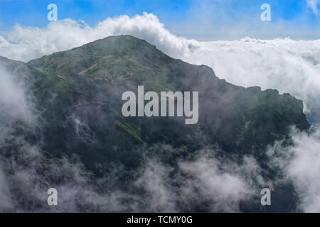 Berg in dichten Wolken vor blauem Himmel. Blick vom Pico Do Arieiro auf der portugiesischen Insel Madeira Stockfoto