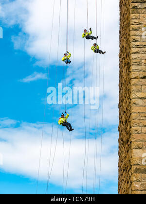 Forth Rail Bridge, South Queensferry, Schottland, Großbritannien. Juni 2019. Charity Abseil: Über 450 Menschen seilen 165 Meter vom Forth Rail Bridge Deck hinunter zum Strand, um Geld für schottische Wohltätigkeitsorganisationen zu sammeln. Eine Sanitäter-Crew, die sich in Unterhemden abseilend Stockfoto