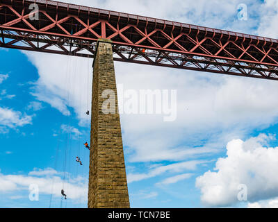 Forth Rail Bridge, South Queensferry, Schottland, Großbritannien. Juni 2019. Charity Abseil: Über 450 Menschen seilen 165 Meter vom Forth Rail Bridge Deck hinunter zum Strand, um Geld für schottische Wohltätigkeitsorganisationen zu sammeln Stockfoto