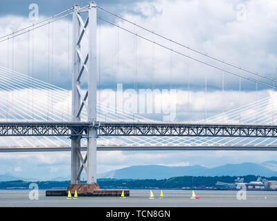 South Queensferry, Schottland, Vereinigtes Königreich, 9. Juni 2019 UK Wetter: Dramatische helle und dunkle Wolken über die Forth Road Bridge und die queensferry Kreuzung mit leuchtend gelben Jollen Erstellen einer krassen Farbe und Größe Kontrast in der Forth River sammeln Stockfoto