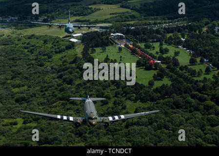 Eine Douglas C-47 Dakota, der den Spitznamen "Das ist Alles, Bruder", Fliegen mit US Air Force C-130J Super Hercules, der 37Th Airlift Squadron, Air Base Ramstein, Deutschland zugeordnet, über die Normandie amerikanische Friedhof und Denkmal in Colleville-sur-Mer, Frankreich, 8. Juni 2019. Des 37th Airlift Squadron Linie Spuren zurück zur 37Th Truppentransporter Squadron, die C-47 s während der Invasion in der Normandie am 6. Juni 1944 flog. (U.S. Air Force Foto von älteren Flieger Devin M. Rumbaugh) Stockfoto