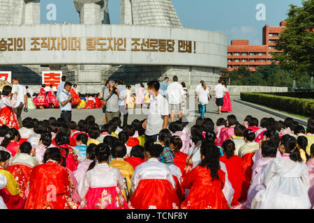 Pyongyang, Nordkorea - Juli 27, 2014: Koreanische Leute sitzen auf dem Platz in Erwartung auf den Beginn der Masse tanzt zu den Tag der Vi gewidmet Stockfoto