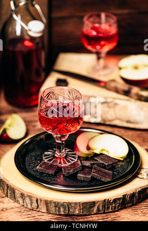 Hausgemachte rote Johannisbeere nalivka und Schokolade mit in Scheiben geschnittenen Apfel auf Metall Fach Stockfoto