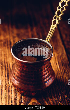 Türkischer Kaffee. Gebrühten Kaffee in Kupfer cezve auf Holz- Oberfläche Stockfoto