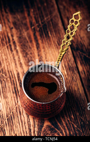 Türkischer Kaffee. Gebrühten Kaffee in Kupfer cezve auf Holz- Oberfläche Stockfoto