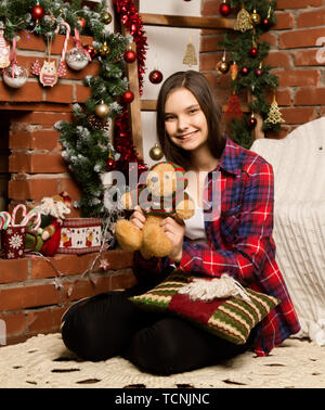 Teenag Mädchen das Lesen eines Buches in der Nähe der Feuerstelle mit Weihnachtsschmuck. Stockfoto