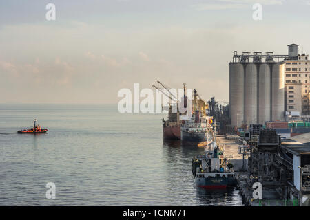 Makassar, Sulawesi, Indonesien - 28. Februar 2019: Grauer Beton zylindrischen Silo Türme mit Schiffen, die in der Port. Stockfoto