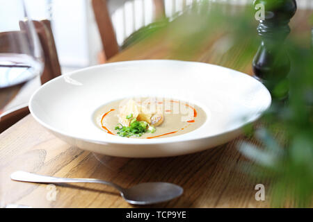 Leckere, schmackhafte Suppe serviert in einer weißen Platte auf einem Holztisch. Vorschlag Vorschlag, Menü. Horizontale Zusammensetzung Stockfoto