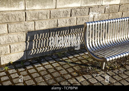 Stahl Sitzbank mit langen Schatten, im Abendlicht. Stockfoto