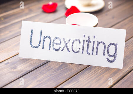 White Paper mit Word unexciting gegen elegante Tasse Kaffee im Cafe Stockfoto