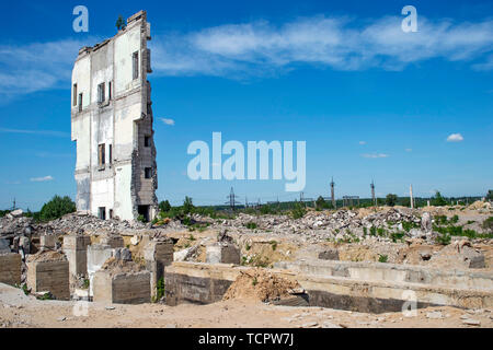 Die Wand des zerstörten großen Gebäude gegen den blauen Himmel mit betonpfählen der Basis im Vordergrund. Hintergrund. Für Text platzieren. Stockfoto