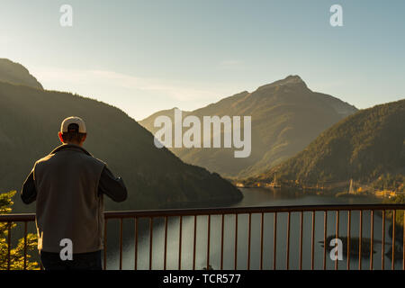 Ein Mann mit Hut und Weste Uhren den Sonnenuntergang über Diablo See von Vista Point in North Cascades National Park. Stockfoto