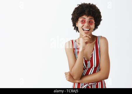 Hey ich tolle Idee. Kreative und stilvolle weibliche afrikanische amerikanische Designer in gestreiften trendigen Overall und rosa Sonnenbrille die Hand auf Ch Stockfoto