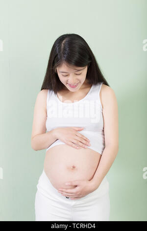 Foto der hübschen schwangeren Frau ihre Hände auf dem Bauch halten. Stockfoto