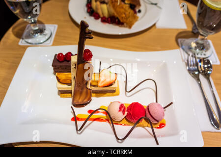 Leckere bunte Schichten von Eis mit frischen Erdbeeren und Kirschen, Schokolade Violine und Spiralen auf weiße Platte, selektiven Fokus Stockfoto