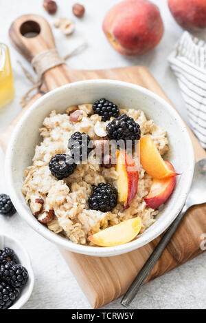 Porridge Schüssel Haferbrei mit Früchten, Beeren, Nüssen und Honig. Ansicht von oben, vertikale Ausrichtung. Konzept von Wohlbefinden, gesunde Ernährung, Diäten und Gewicht l Stockfoto