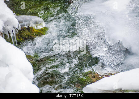 Ein kleiner Wasserfall auf einem Strom in der landschaftlich reizvollen Gegend im Tianshan Tianchi, Xinjiang im Winter ist mit Eiszapfen abgedeckt. Stockfoto