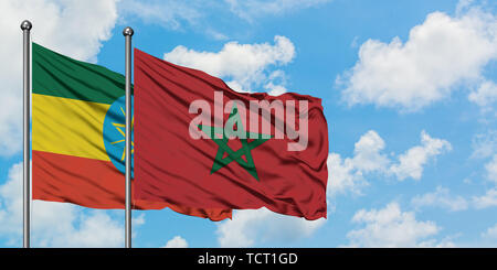 Äthiopien und Marokko Flagge im Wind gegen Weiße bewölkt blauer Himmel zusammen. Diplomatie Konzept, internationale Beziehungen. Stockfoto