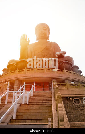 Die enorme Tian Tan Buddha Po Lin Kloster in Lantau Island, Hong Kong. Bei Sonnenuntergang mit orange Sonne hinter der Statue glänzend fotografiert. Beliebte Touristenattraktion. Stockfoto